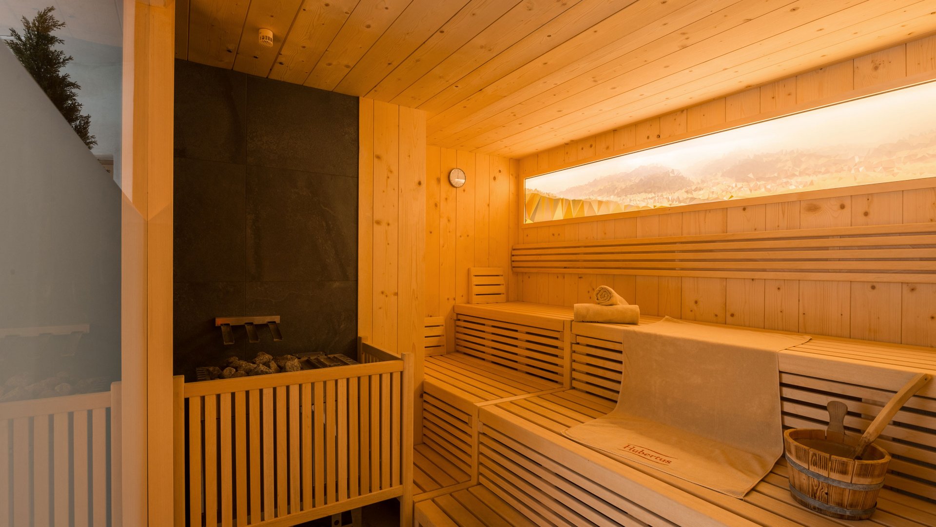 Le nostre saune in Val Pusteria vicino al Plan de Corones Interno sauna in legno moderno con panche, secchio e asciugamani