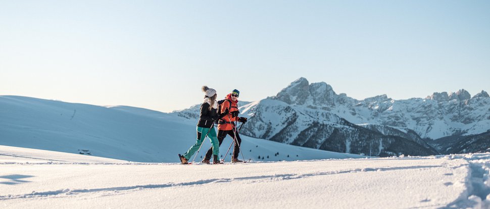 Ultime novità e storie da Valdaora Due persone che fanno escursioni con le ciaspole davanti a montagne innevate