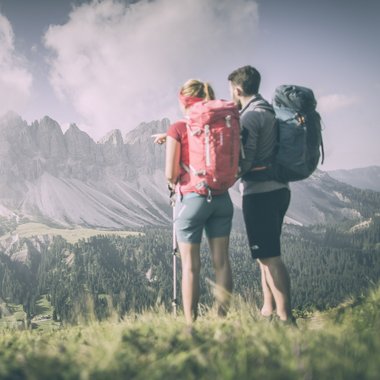 Vacanze in Alto Adige in estate: indimenticabili Due escursionisti con zaini guardano il paesaggio di montagna