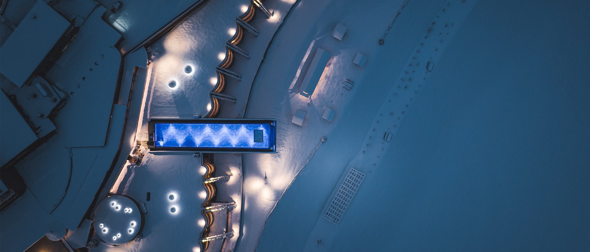 Il nostro hotel con infinity pool in Alto Adige: una meraviglia Vista aerea di una piscina illuminata e paesaggio innevato di notte