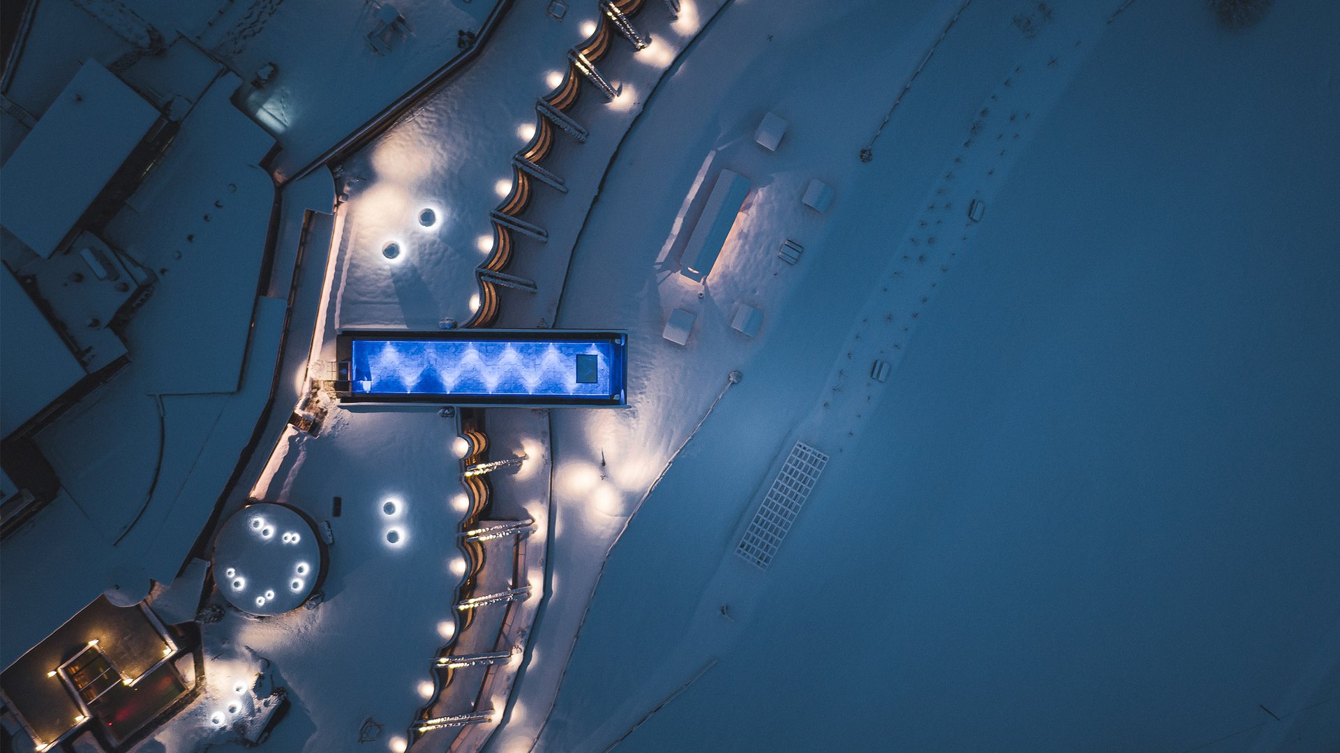 Hotel in Val Pusteria con spa per il vostro relax Vista aerea di una piscina illuminata e paesaggio innevato di notte