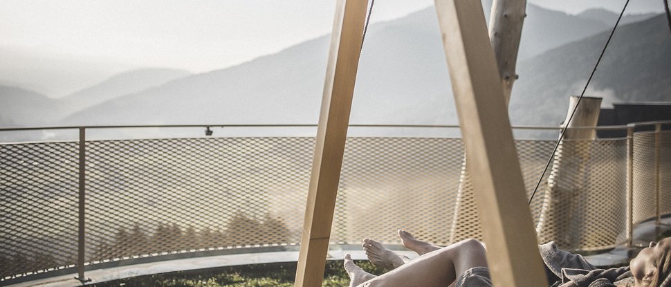 Current news and stories from Olang Person relaxing on a hammock overlooking mountains at sunset