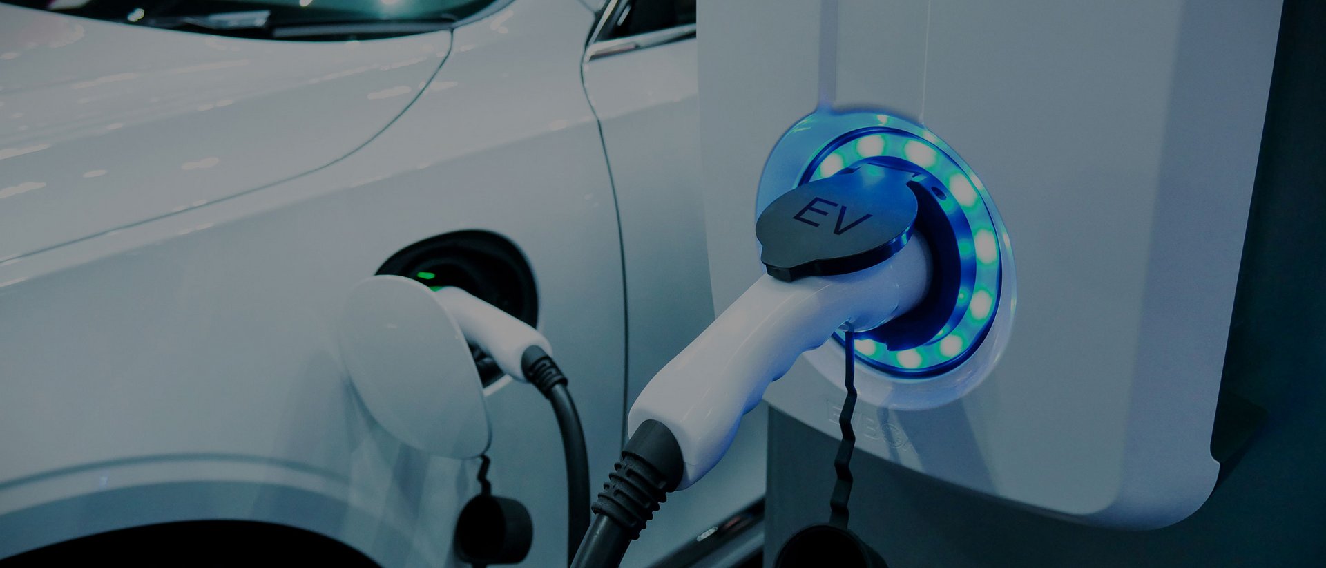 In vacanza in una splendida posizione Auto elettrica bianca in carica presso una stazione di ricarica con luce blu