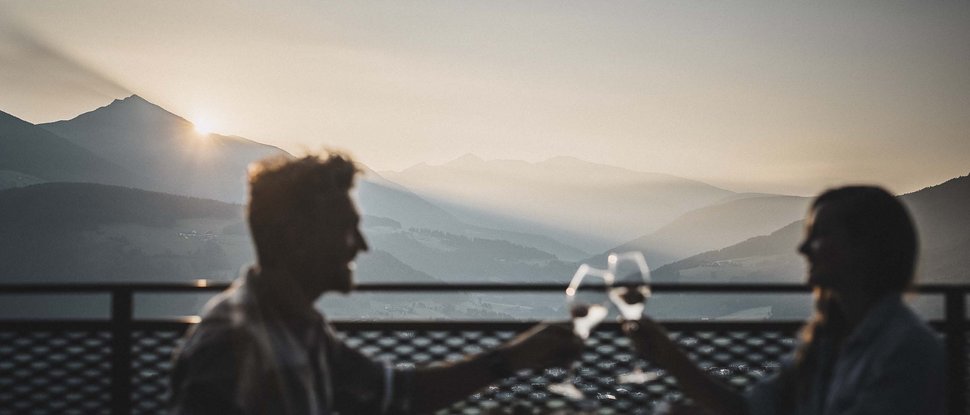 Ultime novità e storie da Valdaora Coppia brinda con bicchieri di vino al tramonto in montagna