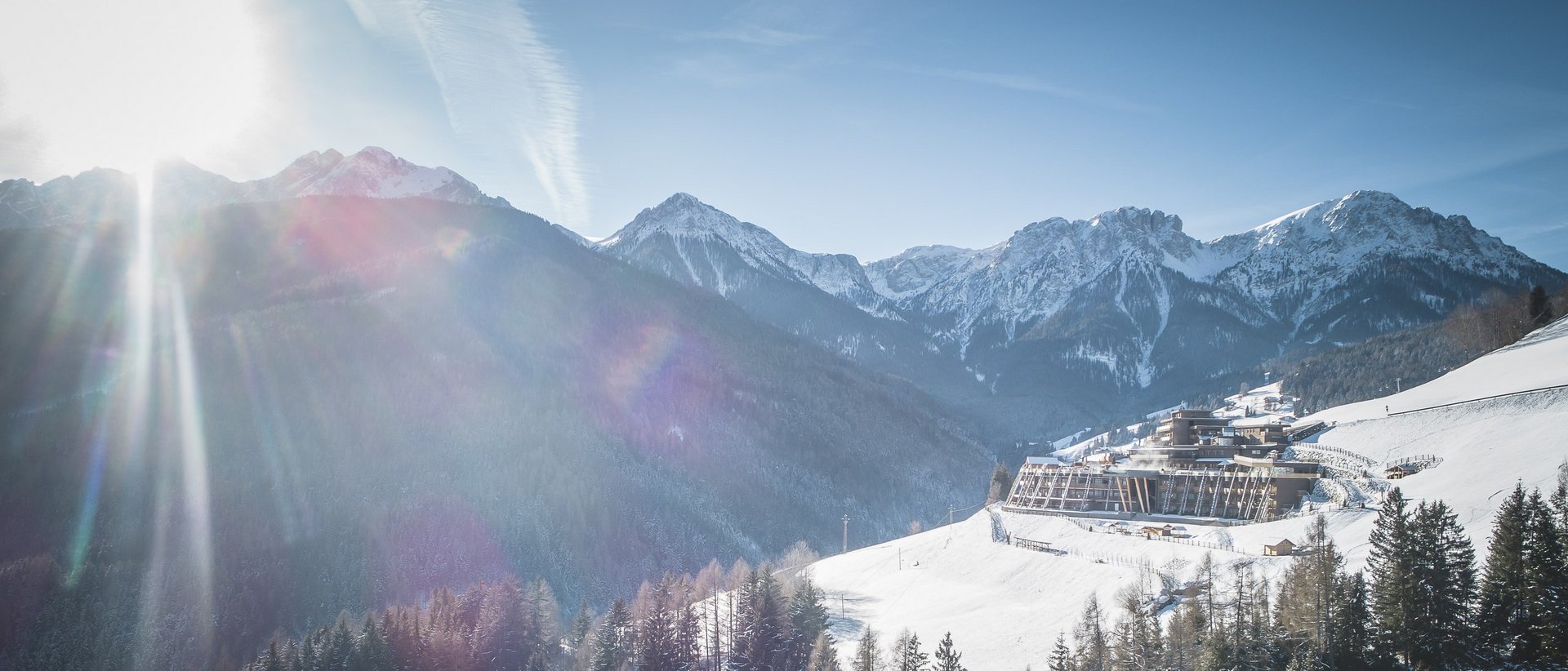 Il nostro hotel a Valdaora tra cielo e terra Giornata invernale soleggiata in montagna con neve, bosco e edificio