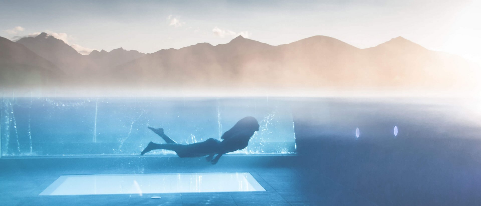 Benessere su tutte le sfaccettature dell’essere Persona che nuota sott'acqua in piscina riscaldata con vista sulle montagne