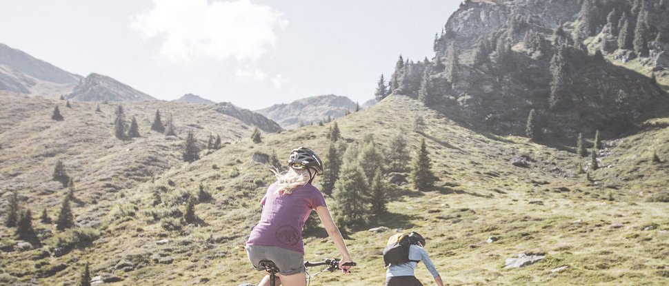 Current news and stories from Olang Two mountain bikers riding on a trail in the mountains on a sunny day