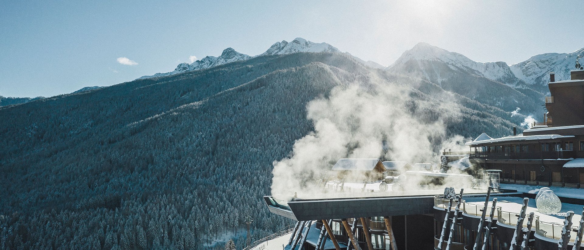 Il nostro hotel a Valdaora tra cielo e terra Hotel di montagna innevato con camino fumante sotto il sole