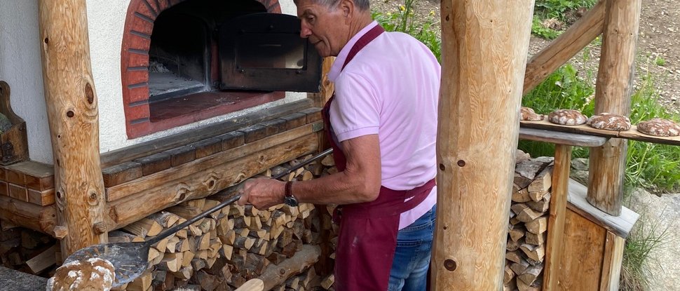 Ultime novità e storie da Valdaora Uomo che cuoce il pane in un forno a legna all'aperto