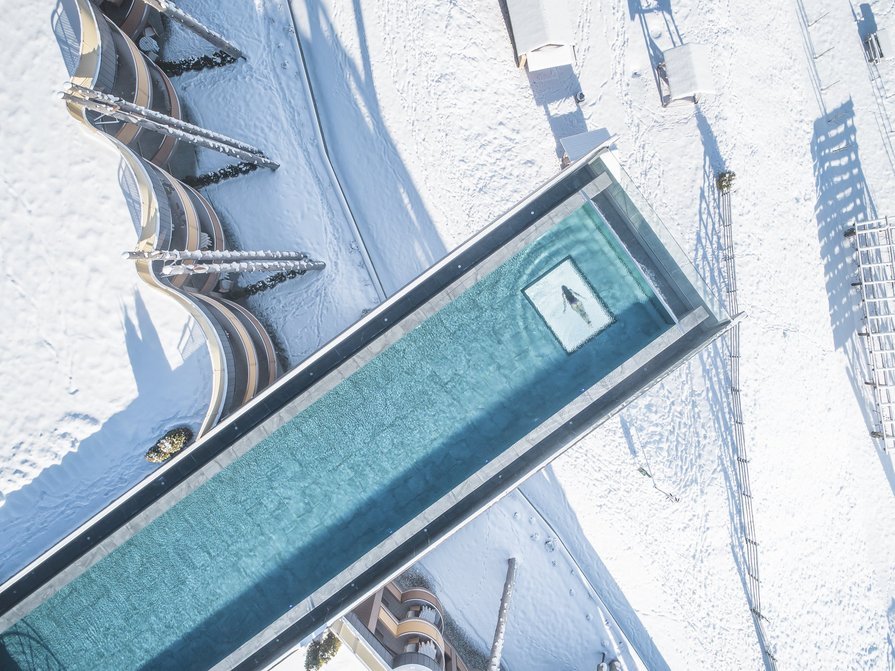 Il nostro hotel a Valdaora tra cielo e terra Vista dall'alto di una piscina riscaldata all'aperto in un paesaggio innevato