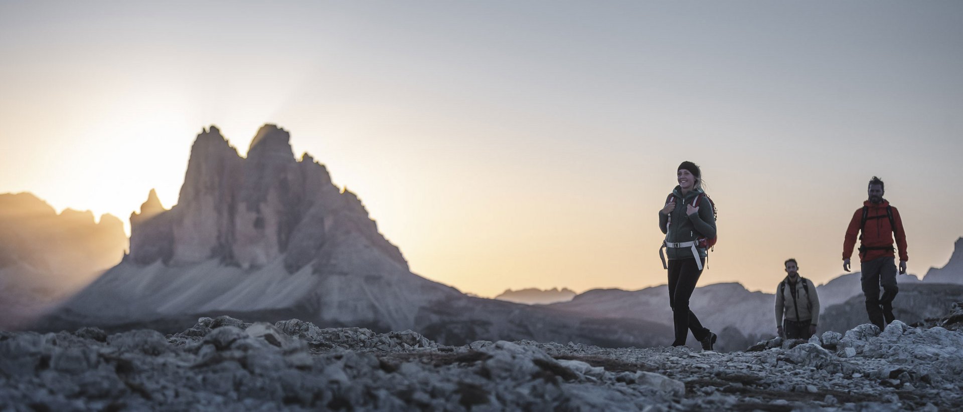 Escursioni a Plan de Corones: uniche Tre escursionisti su sentiero roccioso con montagna al tramonto
