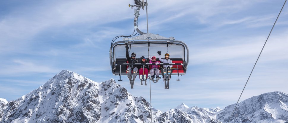 Ultime novità e storie da Valdaora Quattro persone su una seggiovia nelle montagne innevate sotto un cielo limpido