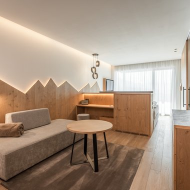 Hotel per cani in Alto Adige: l’Hubertus Camera d'hotel moderna con zona salotto e mobili in legno chiaro