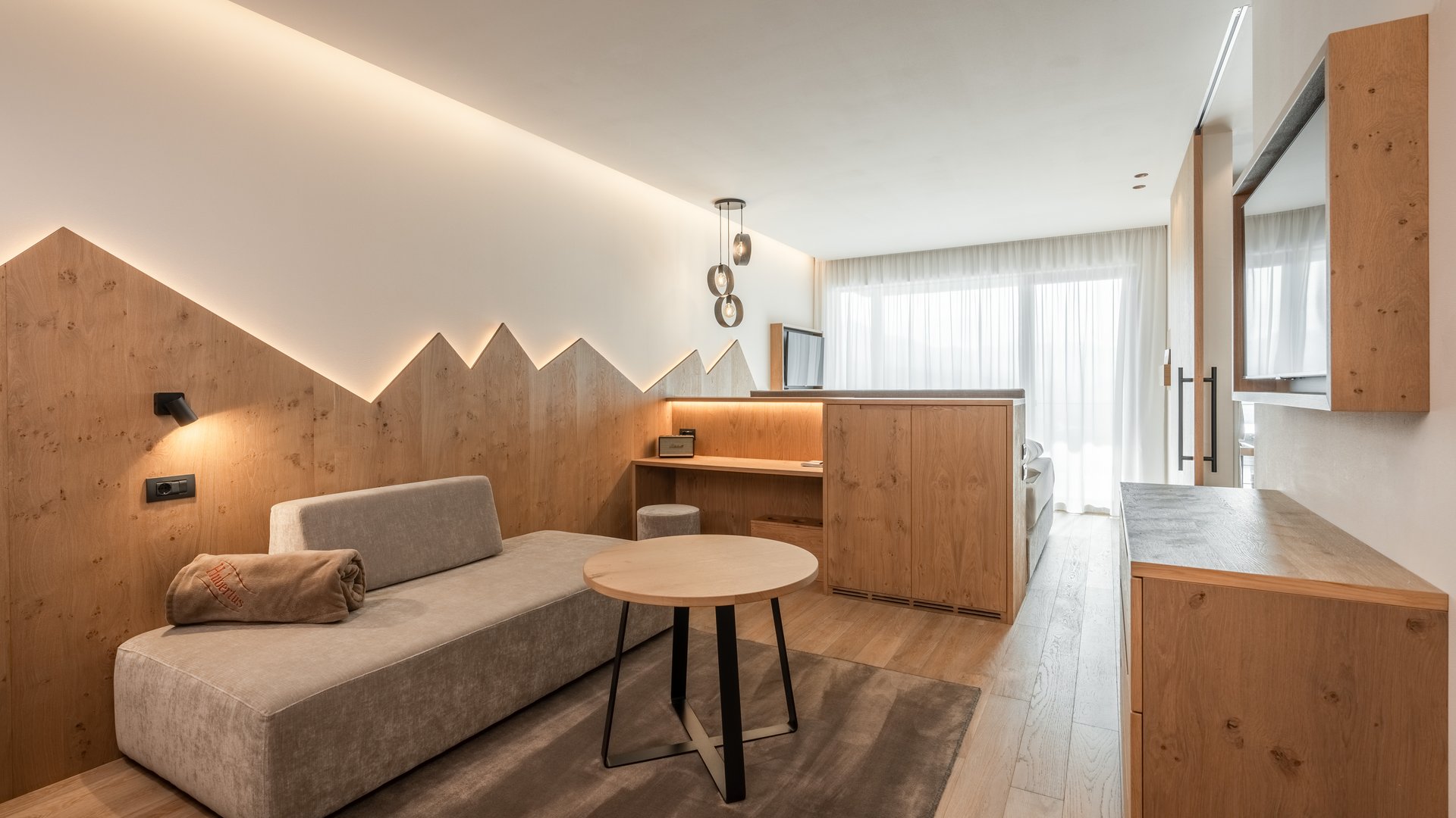 Il nostro buono vacanza: l’Alto Adige in formato regalo Camera d'hotel moderna con zona salotto e mobili in legno chiaro