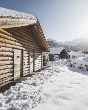I nostri parchi, le vostre oasi di quiete Baite di legno coperte di neve con montagne sullo sfondo sotto cielo sereno