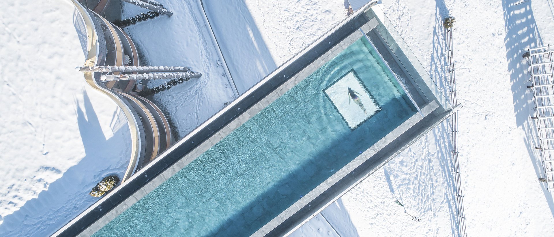 Il nostro hotel con infinity pool in Alto Adige: una meraviglia Piscina sopra un paesaggio innevato con persona che nuota vista dall'alto