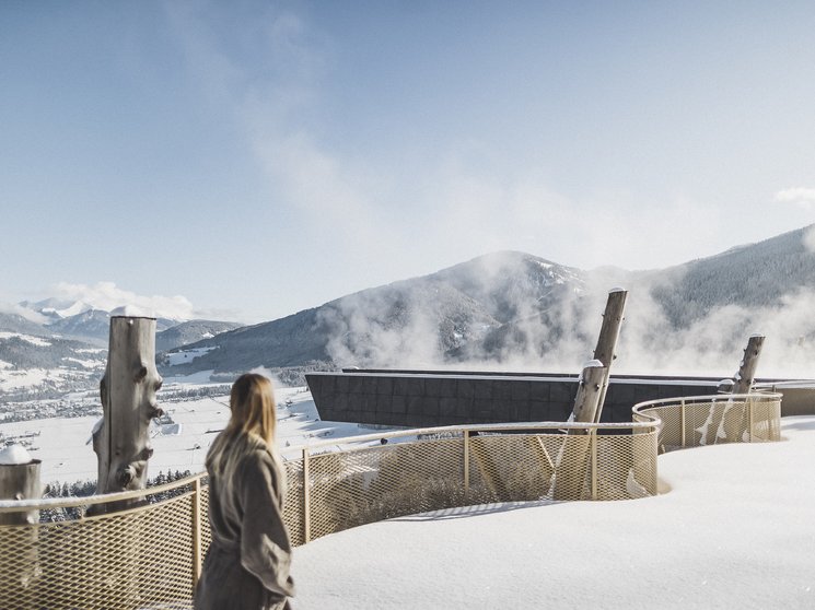 I nostri parchi, le vostre oasi di quiete Persona guarda montagne innevate e edifici fumanti sotto un cielo limpido