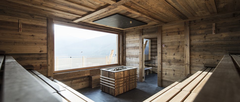 Ultime novità e storie da Valdaora Sauna moderna con pareti e panchine in legno e grande finestra con vista sulle montagne
