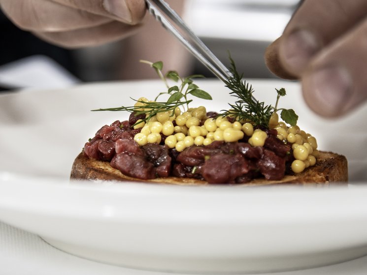 Vivere piaceri culinari stellati Mani che decorano un piatto con erbe fresche e perle gialle