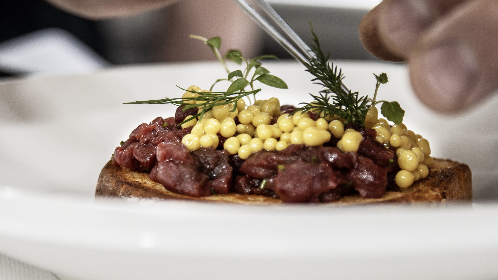 Vivere piaceri culinari stellati Mani che decorano un piatto con erbe fresche e perle gialle
