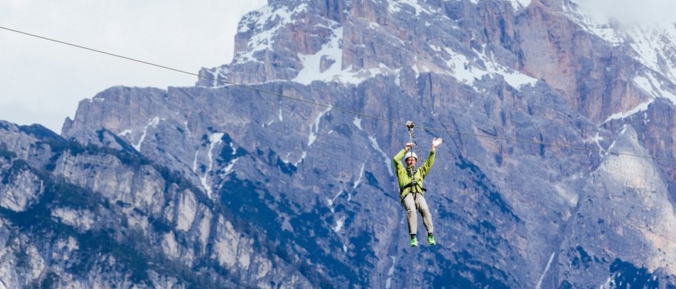 Current news and stories from Olang Person ziplining in front of snow-capped mountains