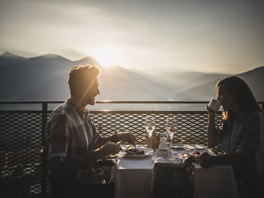 Il nostro hotel a Valdaora tra cielo e terra Coppia che fa colazione con vista sulle montagne al tramonto