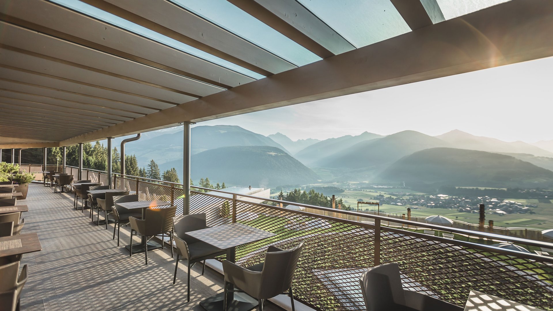 Il regno del gusto Balcone con tavoli e sedie con vista su montagne e valle alla luce del mattino