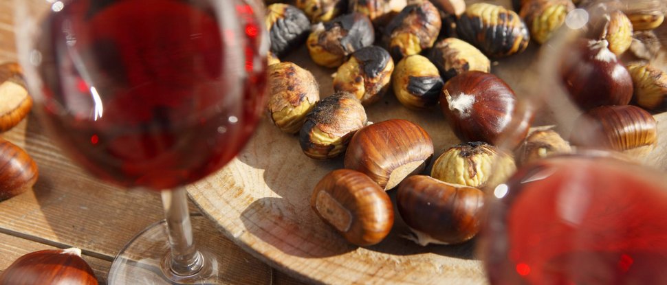 Ultime novità e storie da Valdaora Castagne arrostite su vassoio di legno con bicchieri di vino rosso