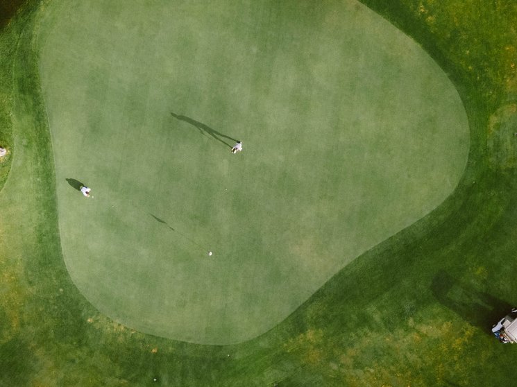 Golf Club Pustertal - Il tuo campo di golf a Plan de Corones Due golfisti sul green con un golf cart sul campo da golf vista aerea