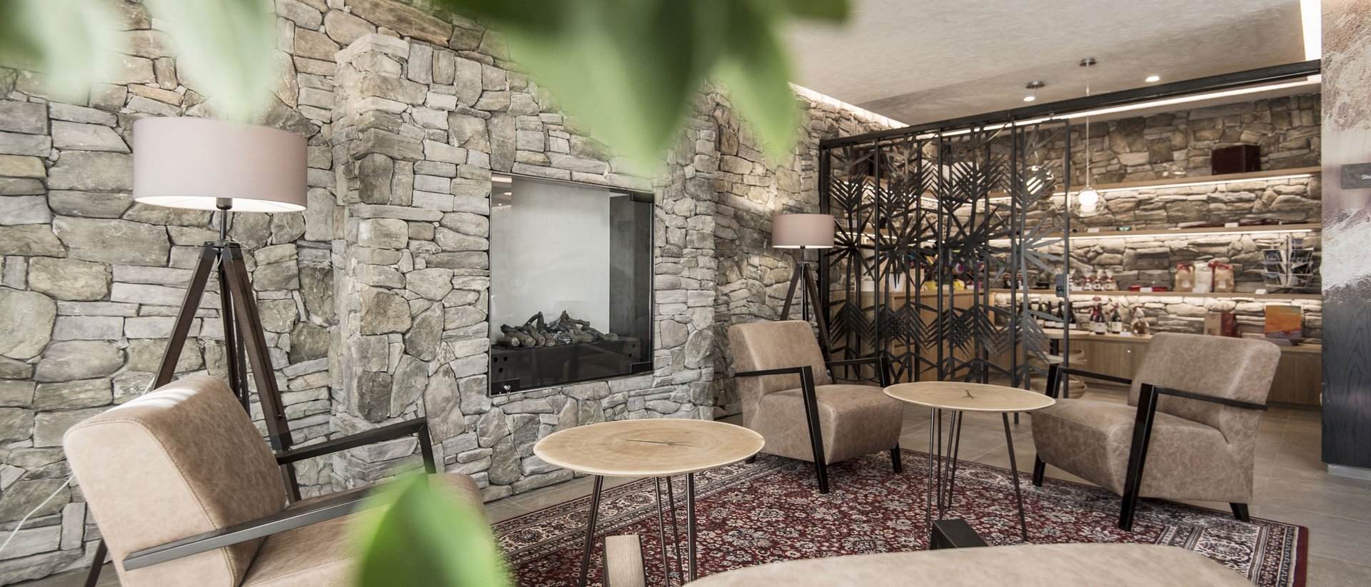 Il nostro albergo in Val Pusteria a conduzione familiare Area salotto accogliente con poltrone in pelle, lampade da terra e parete in pietra