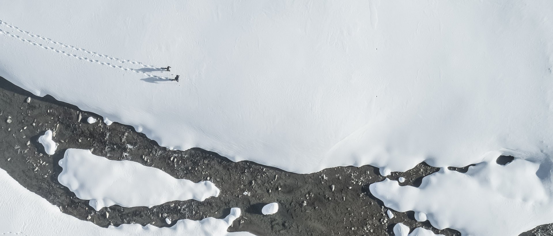 Escursioni invernali in Val Pusteria Foto aereo di paesaggio innevato con due persone e tracce sulla neve