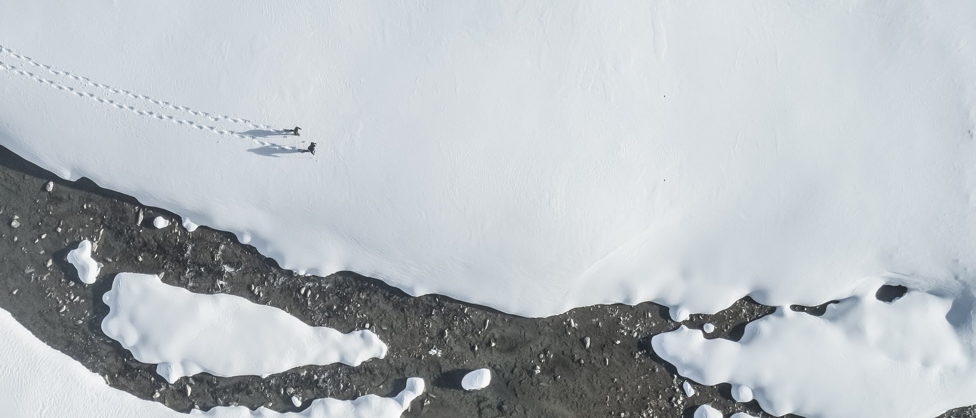 Il nostro hotel a Valdaora tra cielo e terra Foto aereo di paesaggio innevato con due persone e tracce sulla neve