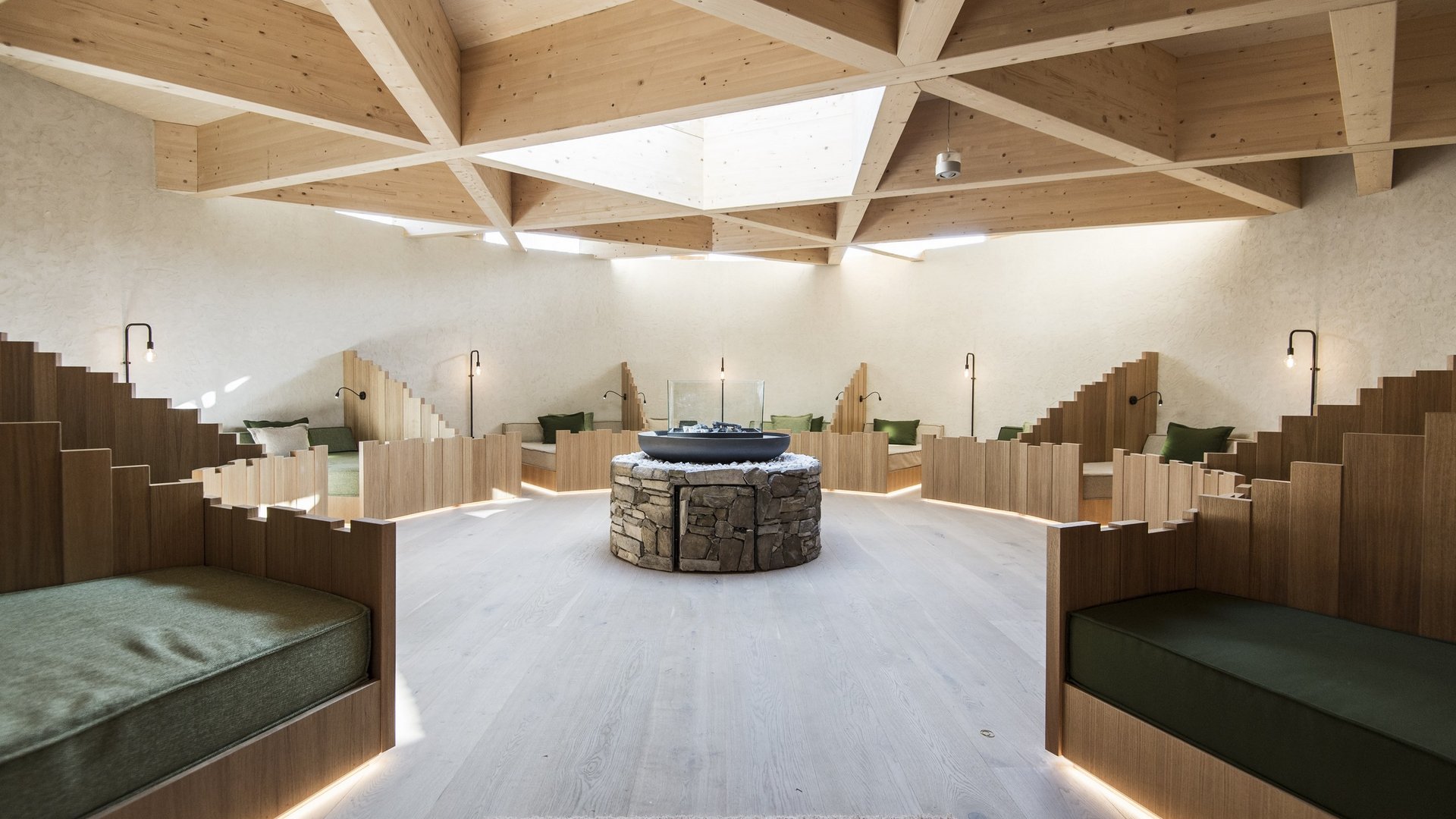 Hotel in Val Pusteria con spa per il vostro relax Area salotto moderna con panche in legno e tavolo centrale in pietra sotto finestra tetto