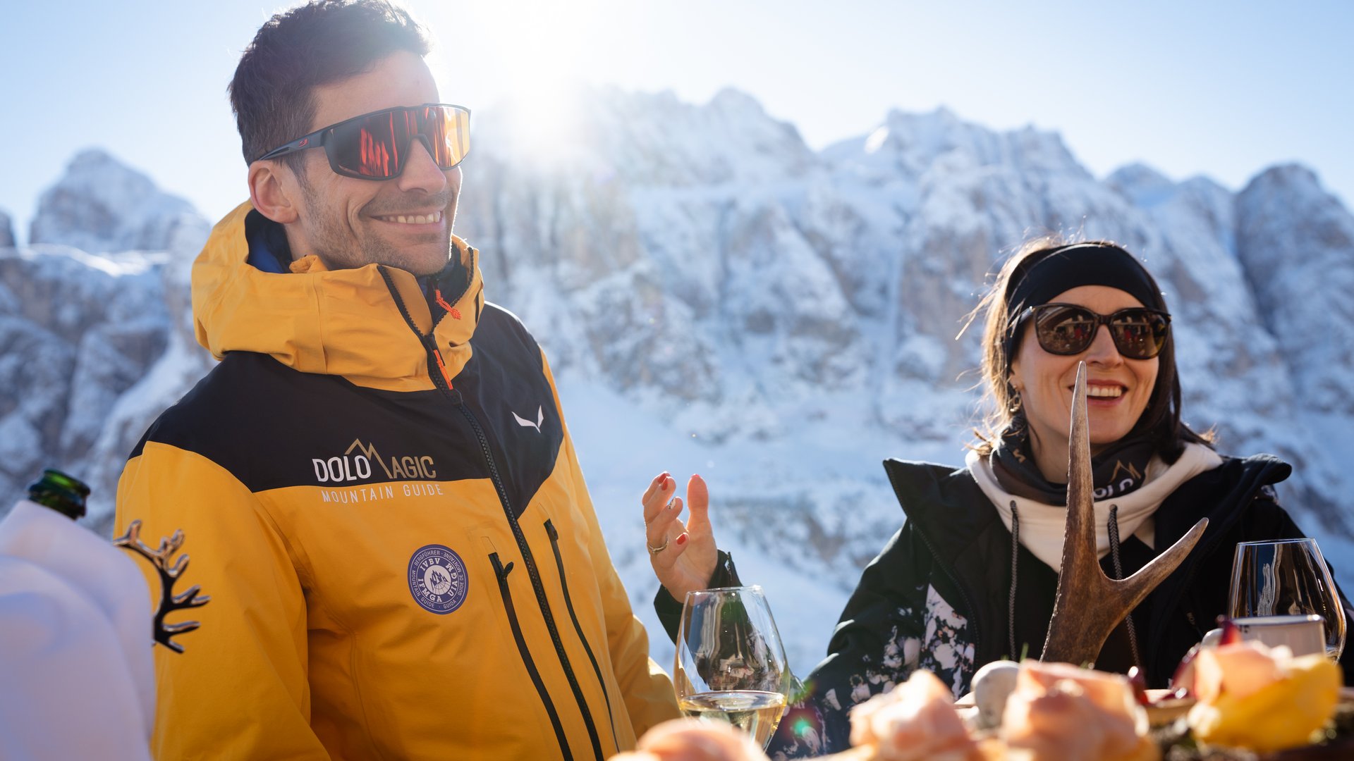 Il miglior hotel sulle piste al Plan de Corones Due persone mangiano all'aperto davanti a montagne innevate con sole