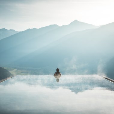 Vacanze in Alto Adige in estate: indimenticabili Persona in piscina infinity con vapore che guarda montagne nebbiose