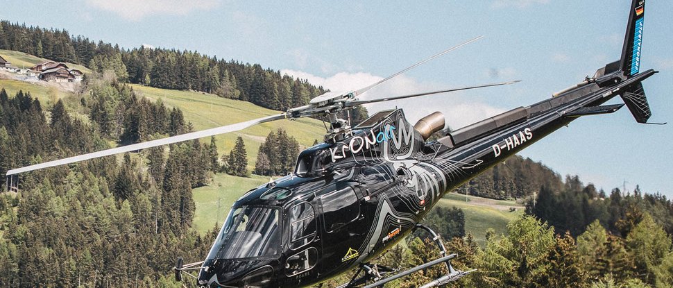 Current news and stories from Olang Black helicopter flying over forested hills with houses in the background