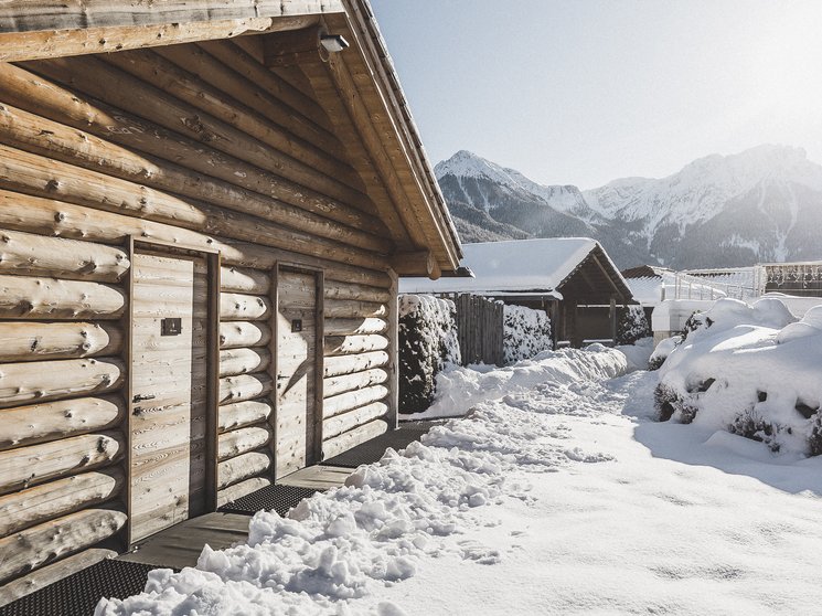 Hotel in Val Pusteria con spa per il vostro relax Casa di legno con tetto innevato davanti a montagne innevate al sole