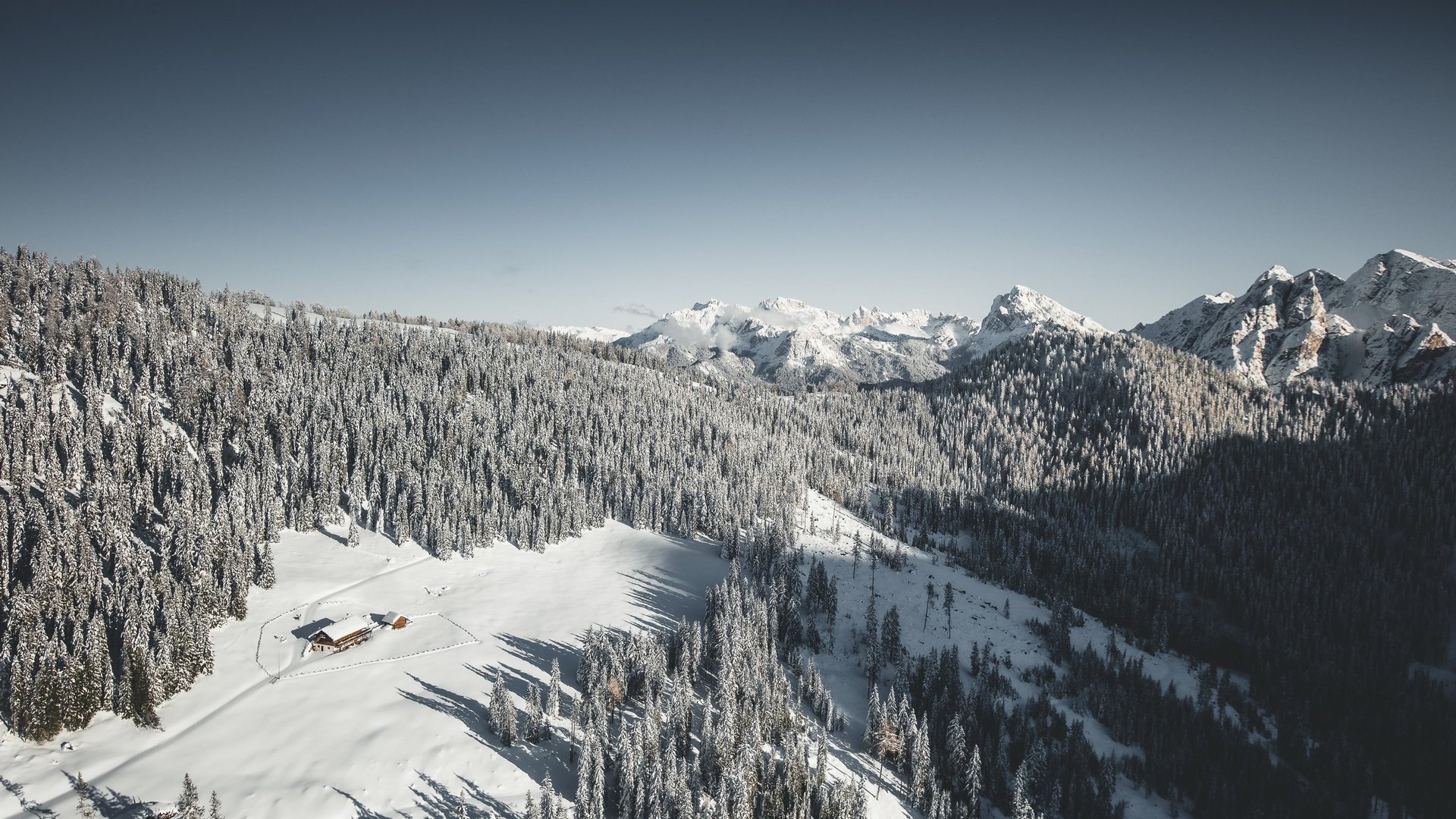 Escursioni invernali in Val Pusteria Casetta di montagna innevata circondata da pini e montagne innevate