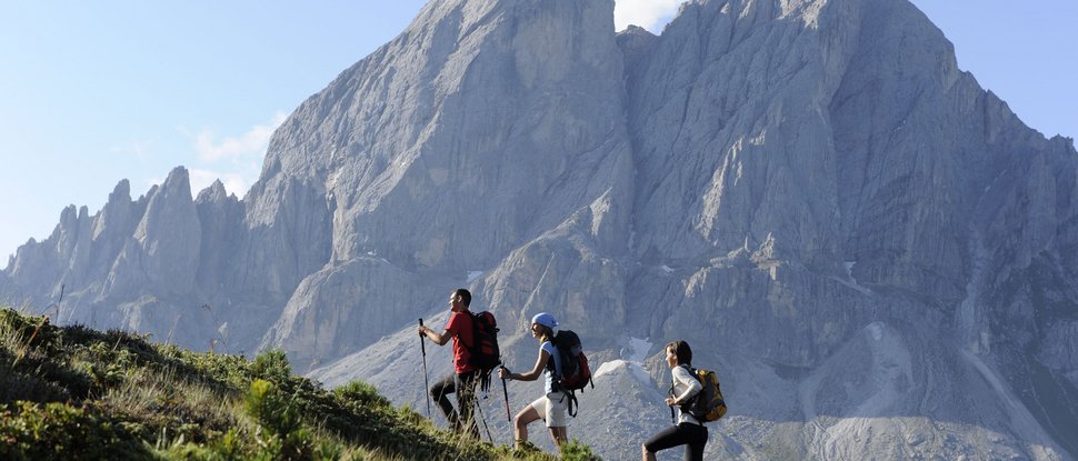 Ultime novità e storie da Valdaora Tre escursionisti che salgono una collina con montagna sullo sfondo