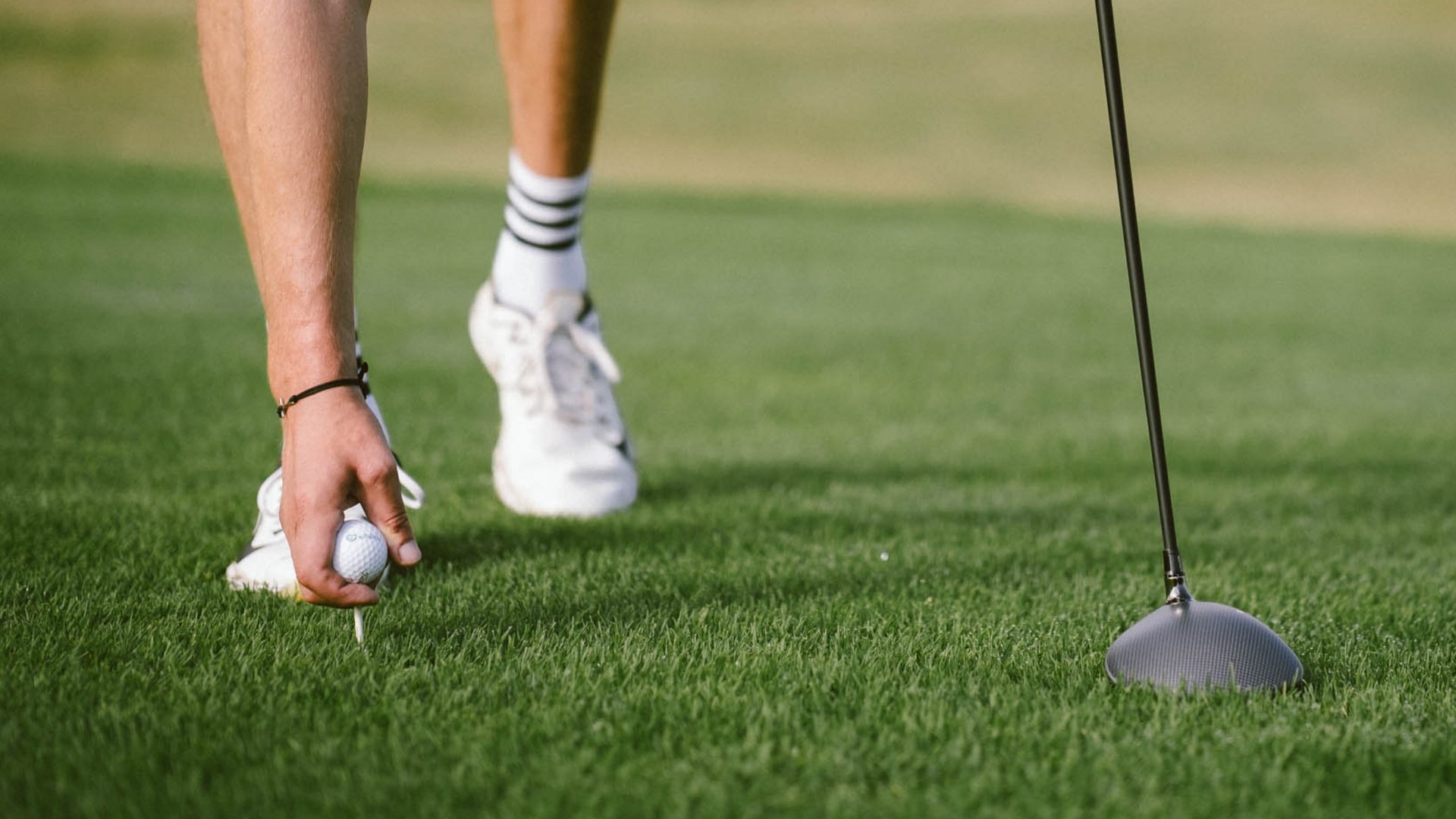 Golfista posiziona la pallina da golf sul tee sull'erba