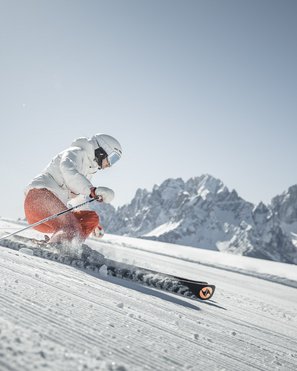 Il nostro buono vacanza: l’Alto Adige in formato regalo Sciatore scende su pista battuta davanti a montagne innevate sotto cielo limpido