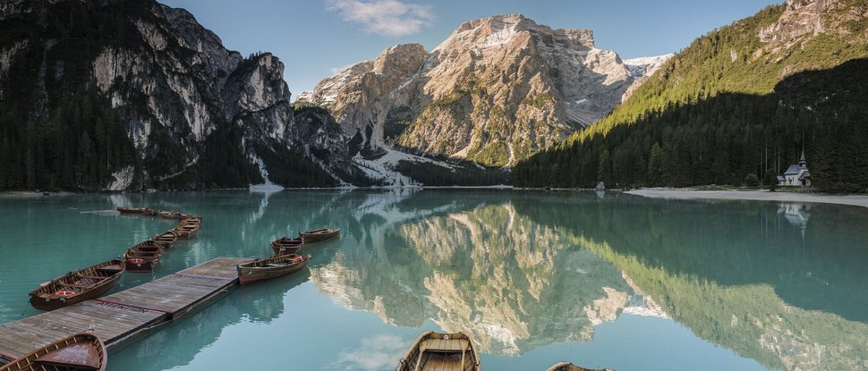 Ultime novità e storie da Valdaora Barche su lago alpino con montagne innevate e foresta