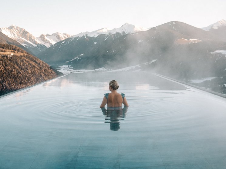 Hotel in Val Pusteria con spa per il vostro relax Donna in piscina a sfioro riscaldata con vista sulle montagne