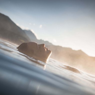 L'Hubertus in un breve lasso di tempo Persona che si rilassa galleggiando sull'acqua con montagne sullo sfondo