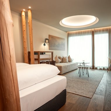 Sostenibilità Camera d'albergo moderna con letto, divano, tavoli e grande finestra con tende