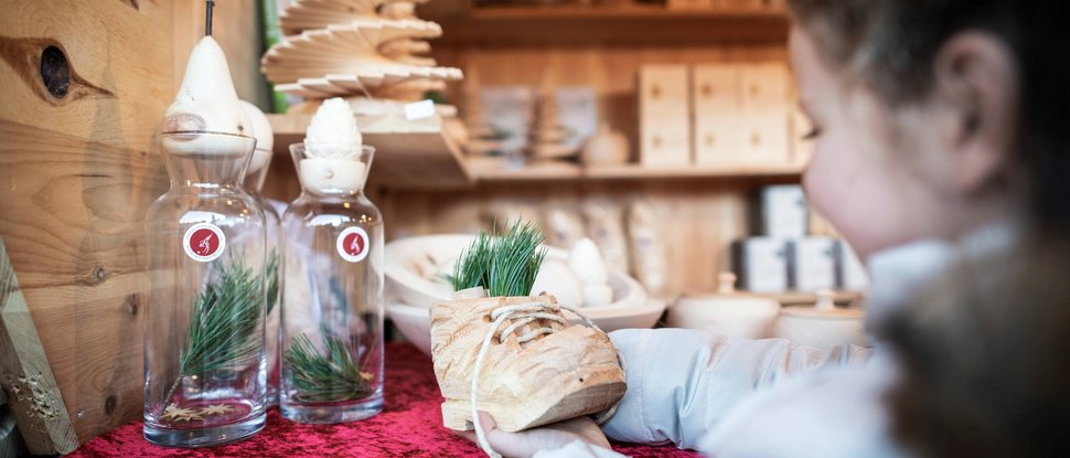 Ultime novità e storie da Valdaora Bambino tiene scarpa di legno intagliata con rami di pino in negozio di Natale