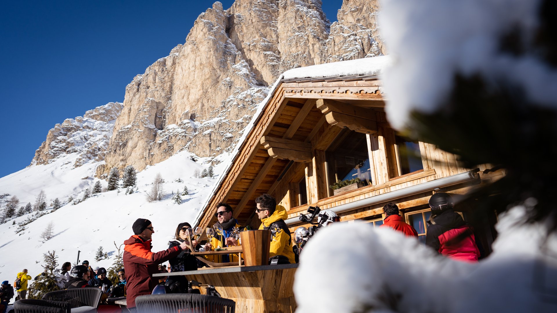Il miglior hotel sulle piste al Plan de Corones Persone che bevono su una terrazza davanti a una baita innevata in montagna