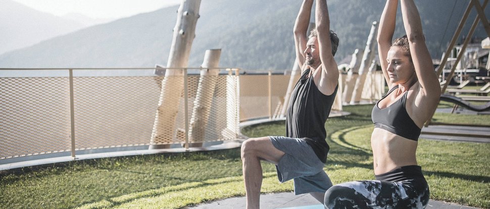 Ultime novità e storie da Valdaora Uomo e donna fanno yoga all'aperto con sfondo montano