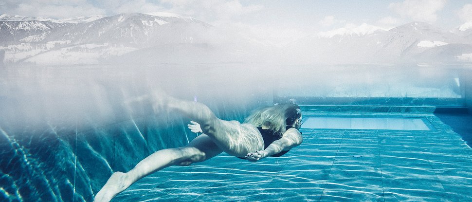 Ultime novità e storie da Valdaora Donna che nuota sott'acqua in una piscina con panorama montano sullo sfondo