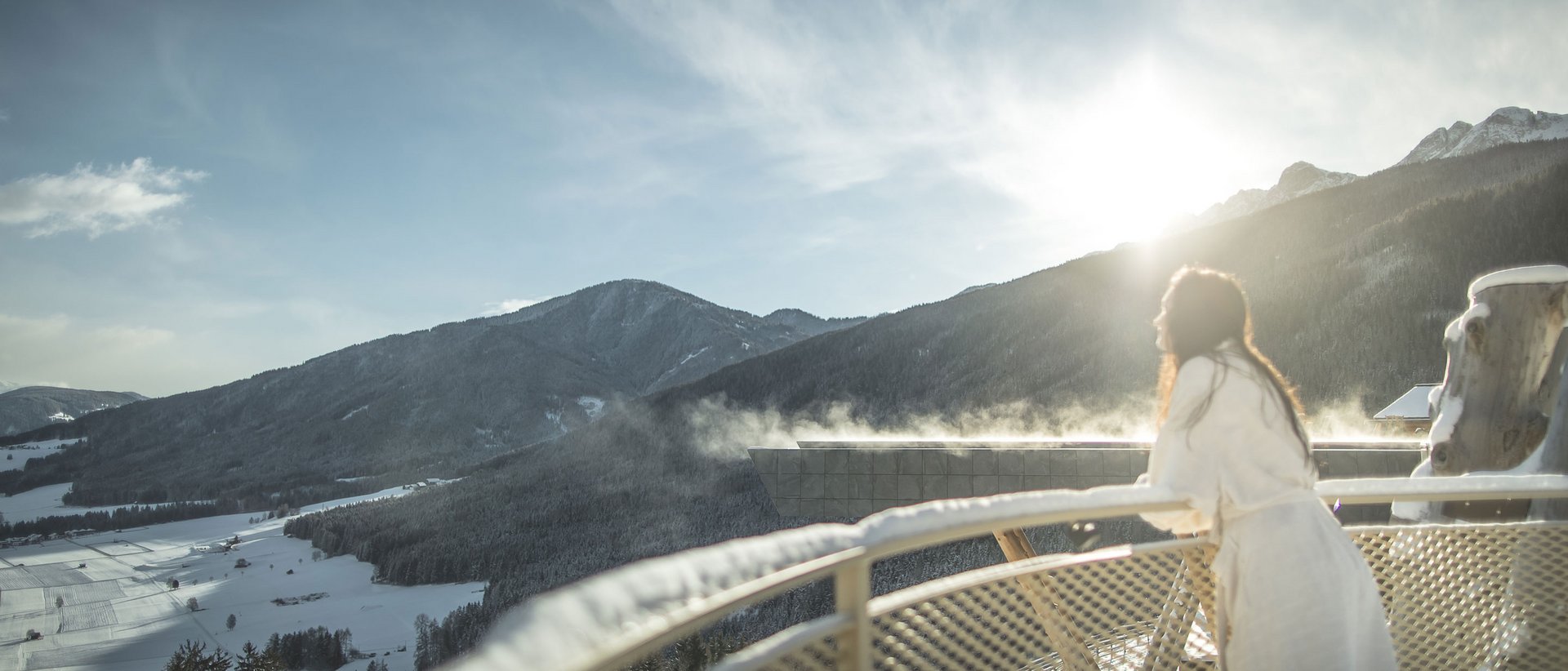 Il nostro hotel con infinity pool in Alto Adige: una meraviglia Donna in accappatoio sul balcone con vista sulle montagne innevate all'alba